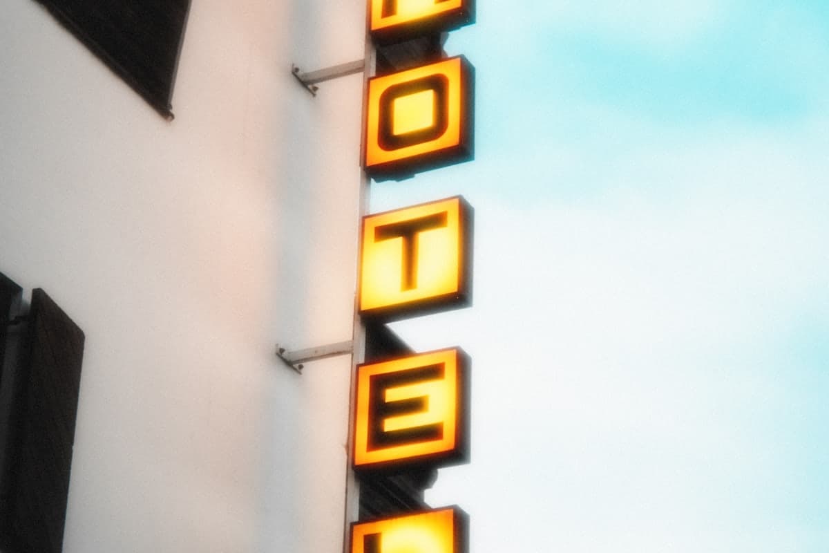 Letrero luminoso de hotel en la fachada de un edificio, recortado contra el cielo